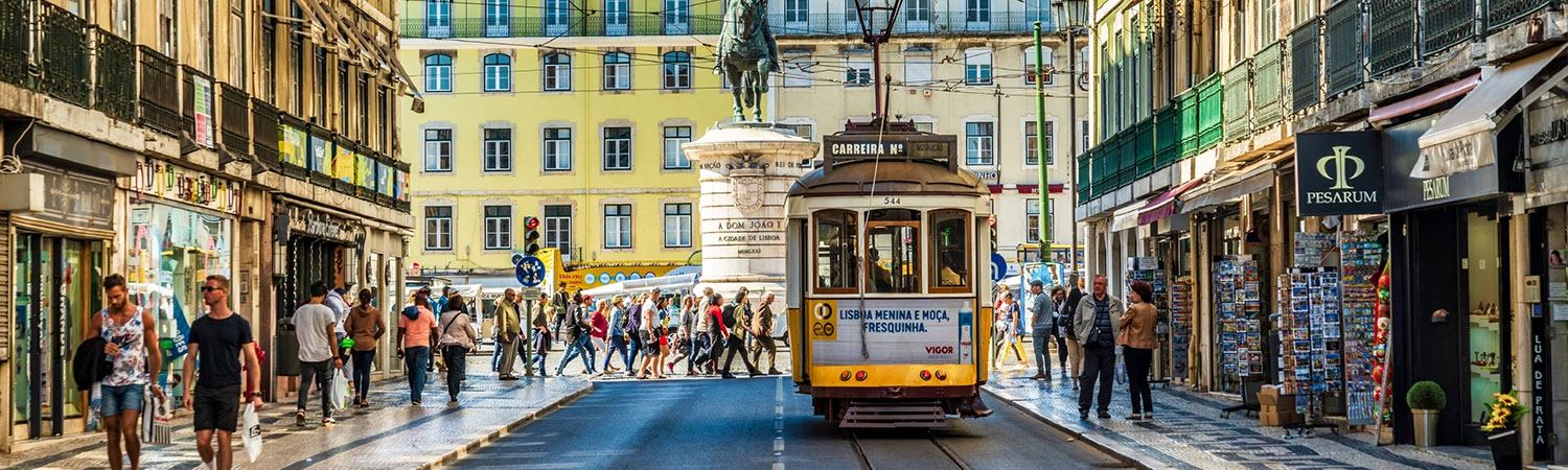 Lisbon’s dynamic street life with a vintage tram, pedestrians, and shops in front of a historic statue and building.