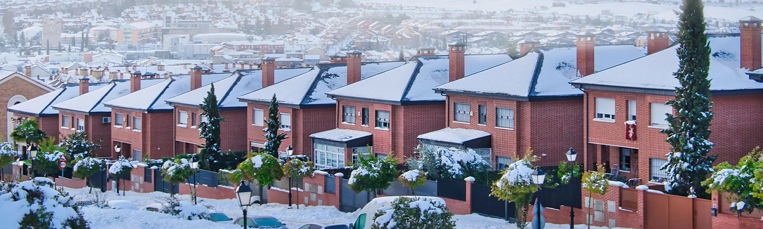 Snow-covered residential area in Madrid, showcasing the serene beauty of red-brick houses with white rooftops, offering a picturesque winter landscape.