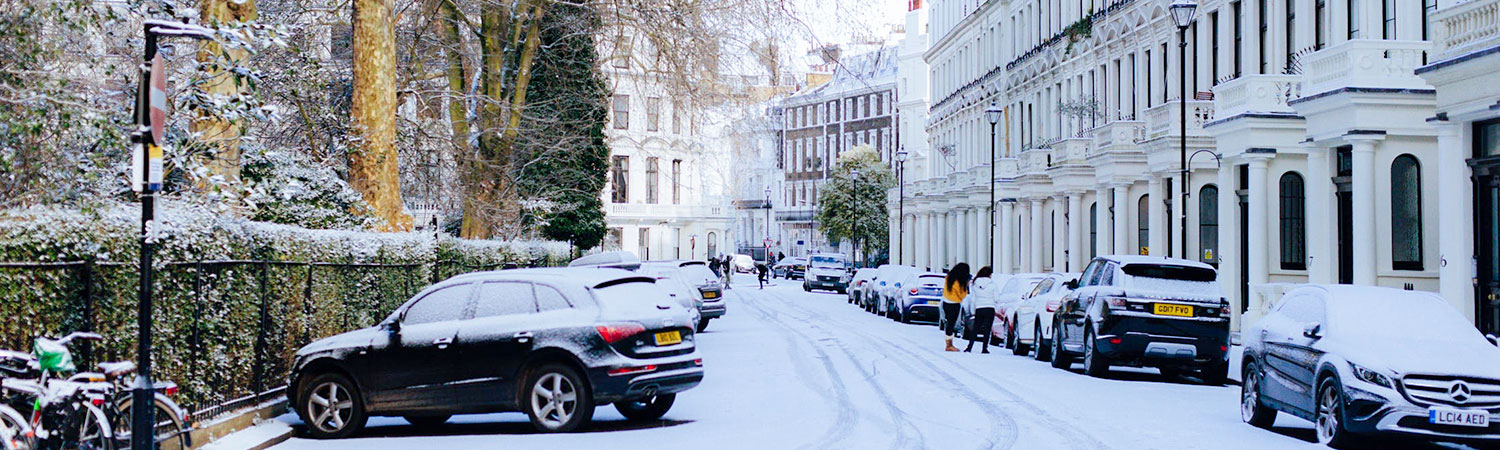  Snowy city street lined with parked cars and classic architecture, creating a serene and picturesque winter scene. 