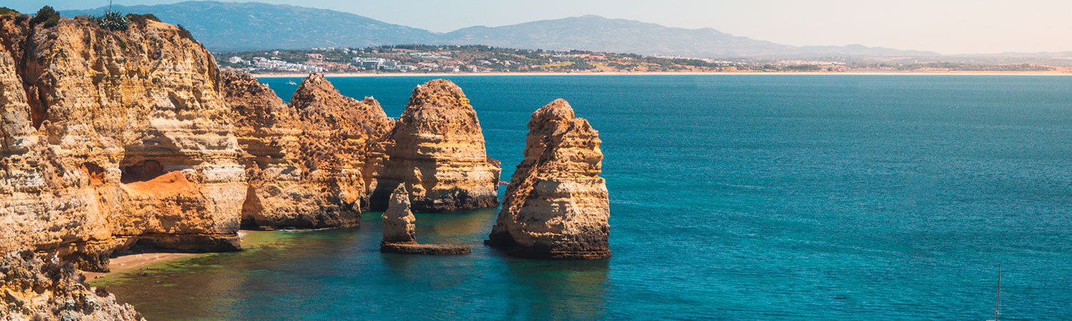 A breathtaking view of the golden, rocky cliffs contrasting with the serene blue waters at the famous Algarve coast in Portugal.