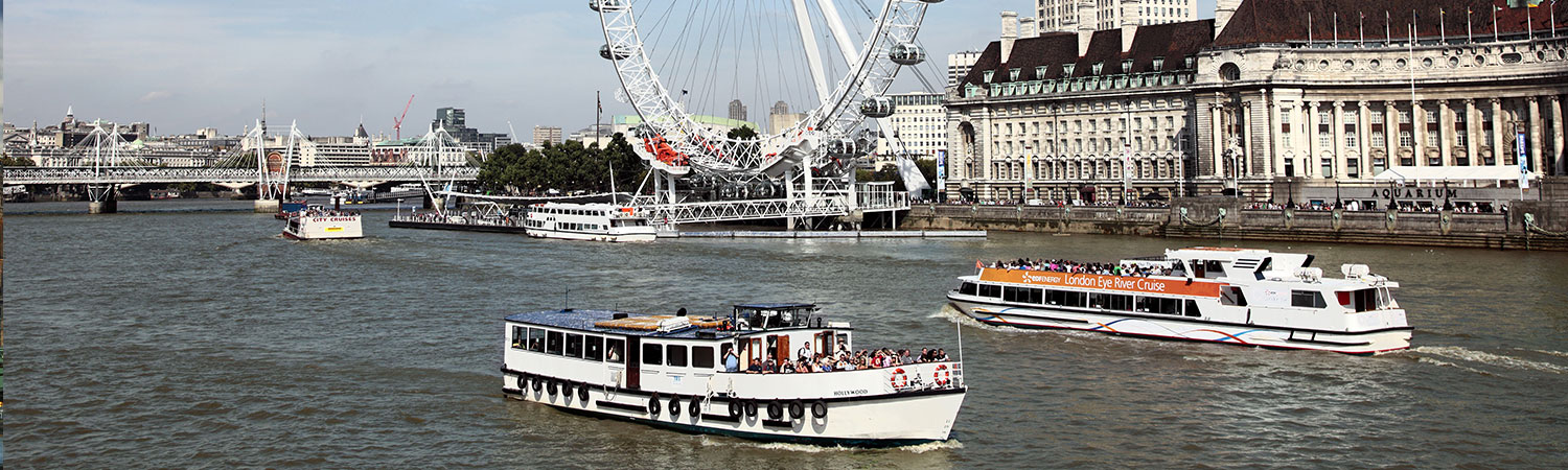 A panoramic view of the iconic London Eye and the bustling River Thames, featuring cruise boats and London’s historic architecture.