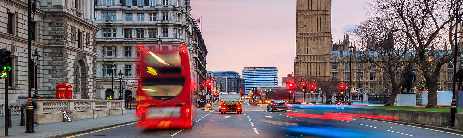 A bustling London street scene at dusk, featuring the iconic red double-decker bus and Big Ben in the backdrop.