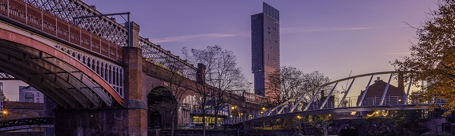 A scenic view of Manchester’s iconic bridges and modern architecture at dusk, highlighting the blend of historical and contemporary structures.