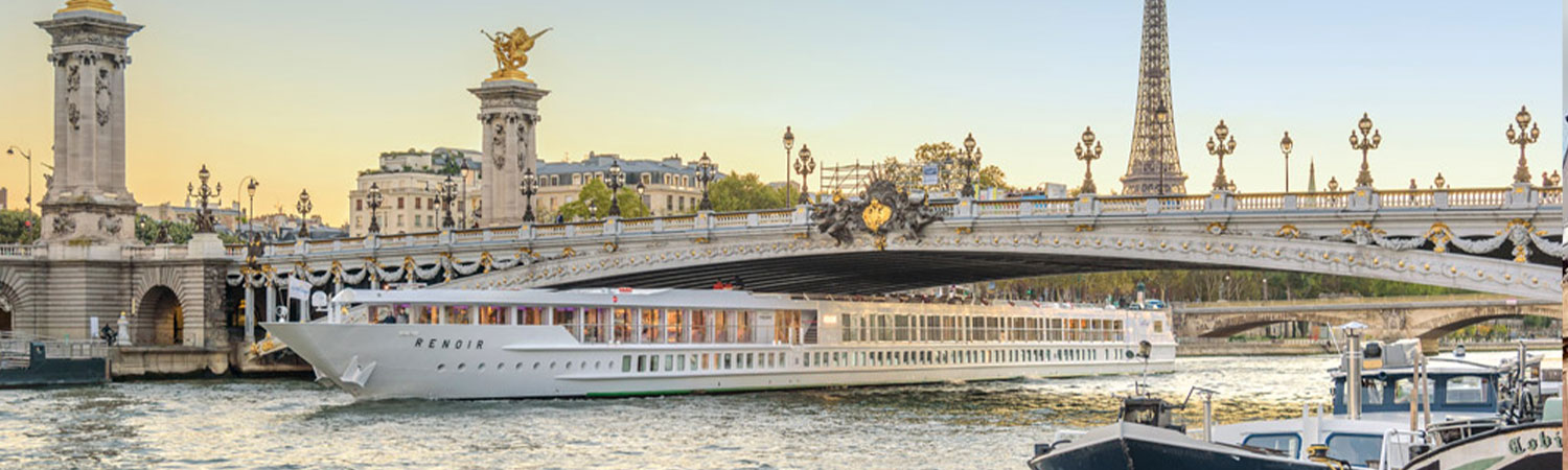 A panoramic view of the iconic Pont Alexandre III bridge with ornate lampposts and golden statues, overlooking the Seine River where the “Renoir” cruise ship sails, with the Eiffel Tower in the backdrop, capturing the essence of Paris.
