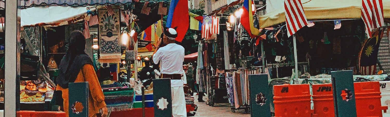 Outdoor market with colorful textiles and flags.
