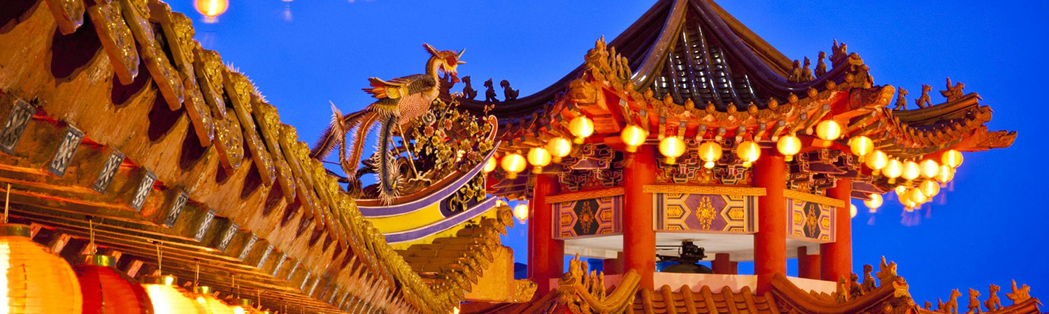 Traditional Chinese architecture with phoenix sculpture, red lanterns, and pagoda at dusk.