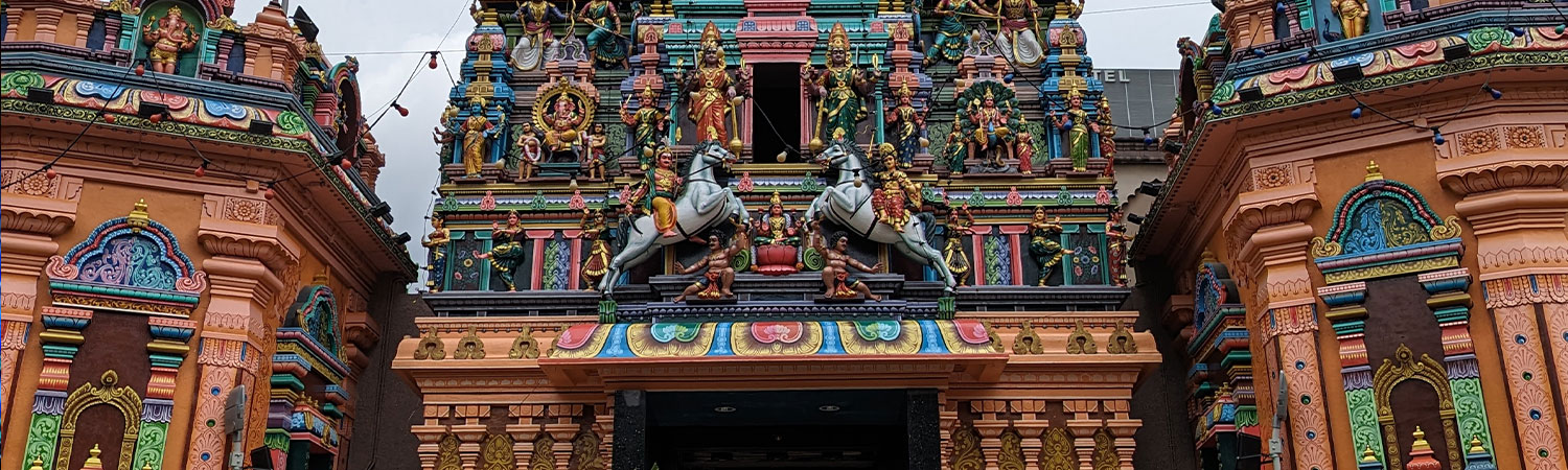 Colorful Hindu temple facade with deity statues and horses in Malaysia.