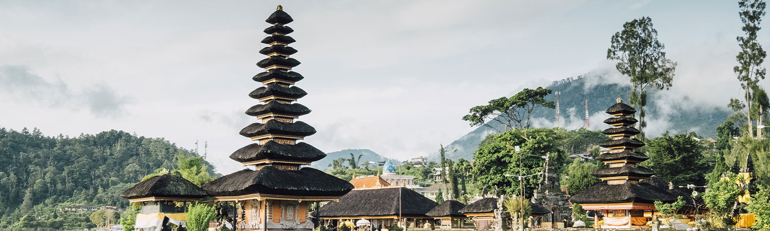 Panoramic view of the iconic Besakih Temple amidst the lush green landscape of Mount Agung, Bali, showcasing intricate Balinese architecture.