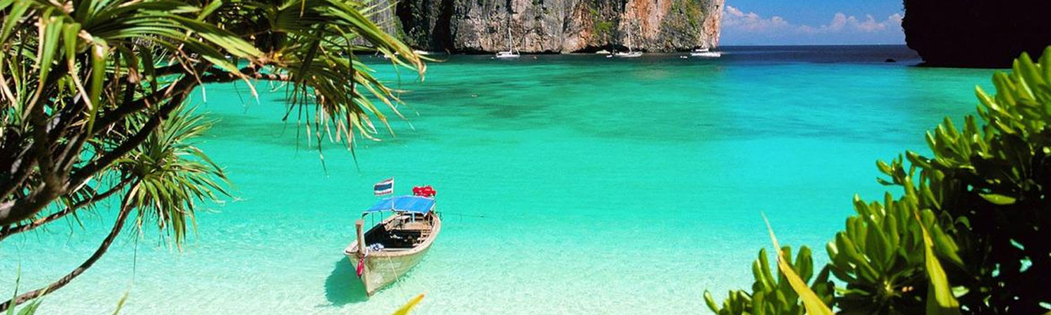 Serene tropical beach scene with crystal clear turquoise waters, a lone boat adorned with red flowers anchored near the shore, surrounded by lush greenery and towering cliffs under a clear blue sky.