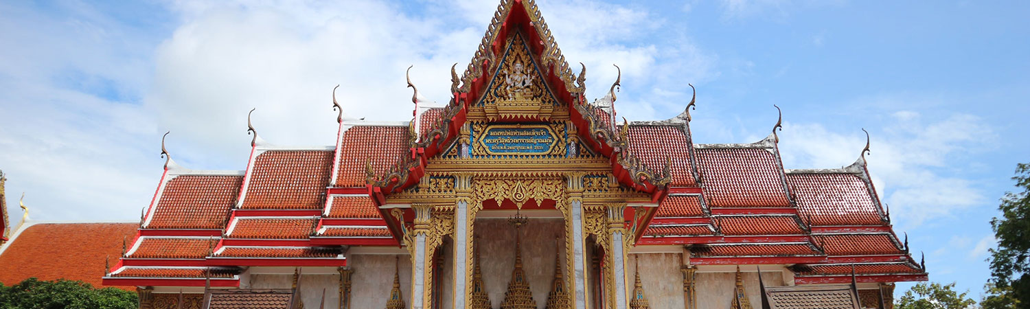 Panoramic view of the majestic Wat Nong Khem branch 1, a traditional Thai temple with intricate gold detailing and vibrant red roofs, under a clear blue sky in Thailand.