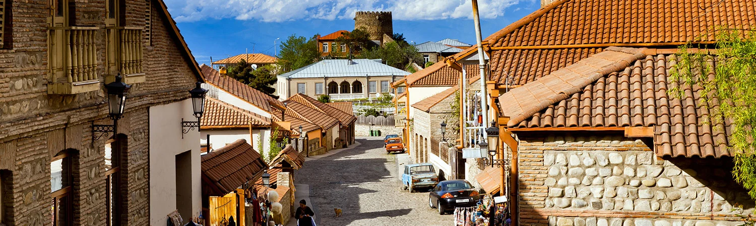 A picturesque street in a town with historical architecture and a tower on a hill