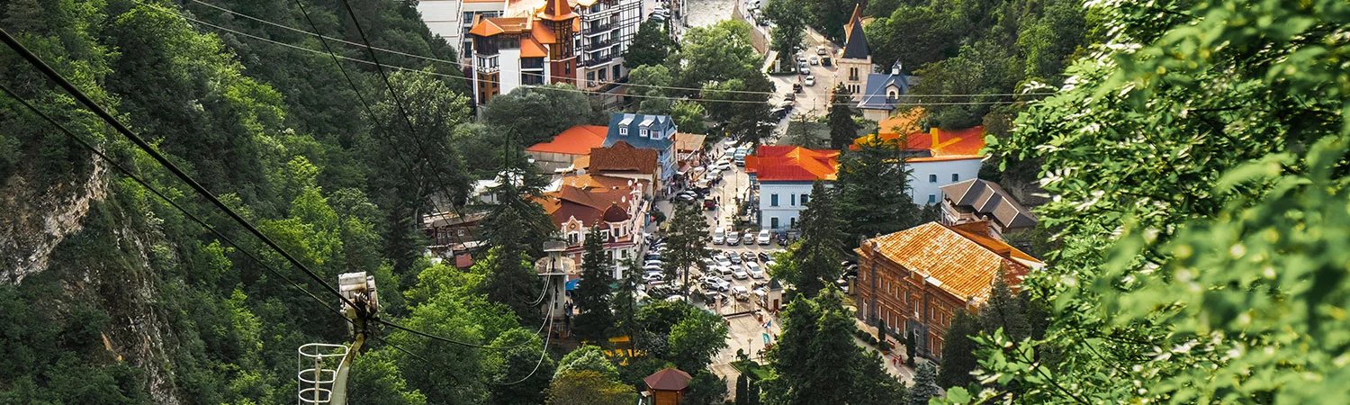  A scenic view of a vibrant town in Georgia, showcasing lush greenery, architectural beauty, and a cable car system connecting the picturesque landscape.