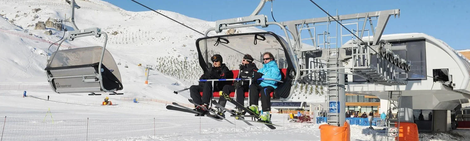Skiers riding a chairlift at a snowy mountain resort.