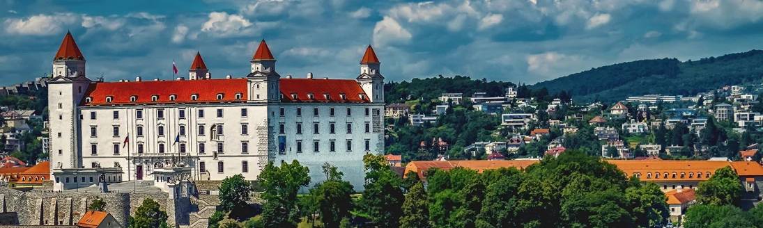 A panoramic view of the iconic Bratislava Castle, majestically standing against the backdrop of a picturesque cityscape and lush greenery in Bratislava, Slovakia.