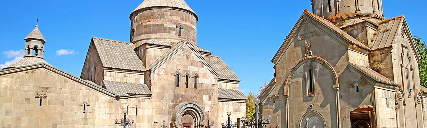 A panoramic view of an ancient stone church with intricate architectural designs, set against a clear blue sky.